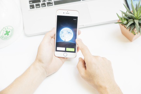 Bangkok,Thailand March 4 2017 : Notebook and safety helmet and hand holding iPhone 6 with social network service Wechat on the screen. iPhone was created and developed by the Apple inc.のeditorial素材