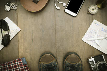 Travel accessories costumes. Passports, luggage, hat,guitar, travel maps,camera prepared for the trip place on brown wood texture,retro tone with vignetteの写真素材