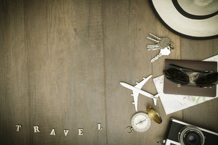 Travel accessories costumes. Passports, luggage, hat,guitar, travel maps,camera prepared for the trip place on brown wood texture,retro tone with vignetteの写真素材