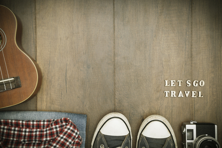 Travel accessories costumes. Passports, luggage, hat,guitar, travel maps,camera prepared for the trip place on brown wood texture,retro tone with vignetteの写真素材