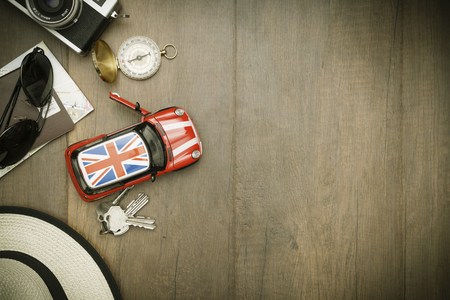 Travel accessories costumes. Passports, luggage, hat,guitar, travel maps,camera prepared for the trip place on brown wood texture,retro tone with vignetteの写真素材