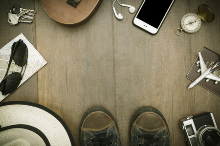 Travel accessories costumes. Passports, luggage, hat,guitar, travel maps,camera prepared for the trip place on brown wood texture,retro tone with vignetteの写真素材
