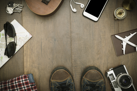 Travel accessories costumes. Passports, luggage, hat,guitar, travel maps,camera prepared for the trip place on brown wood texture,retro tone with vignetteの写真素材