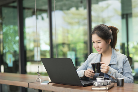 Smiling business asian woman used laptop and smart phone in coffee shop,business concept.の写真素材