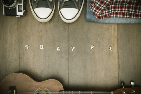 Travel accessories costumes. Passports, luggage, hat,guitar, travel maps,camera prepared for the trip place on brown wood texture,retro tone with vignetteの写真素材