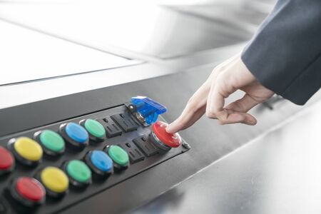 Woman pushing red or emergency button on dash board for stop machine.の写真素材