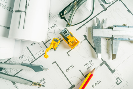 Top view of architech drawing on non identified architectural project with various of tools such as divider pencil eye glassed and small heavy equipment machine toysの写真素材