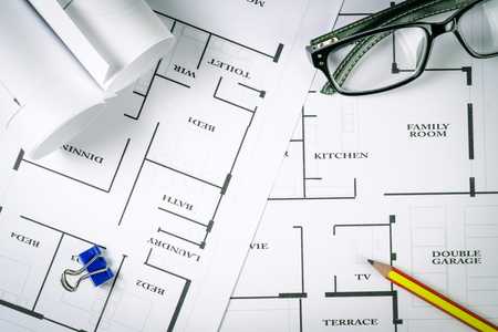 Top view of architect drawing on non identified architectural project with various of tools such as divider pencil eye glassed and small heavy equipment machine toysの写真素材