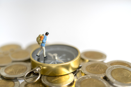 Miniature toy:Young hipster tourist planning saving money for tour on compass and coins : tour ,saving money ,adventure concept.の写真素材