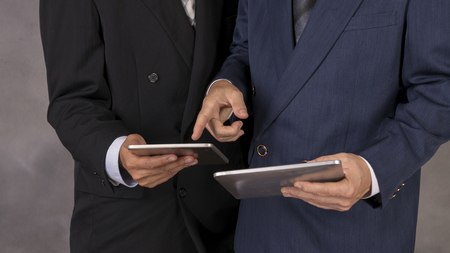 Young happy businessmen dressed in suit working on his tablet or touchpad in office.の写真素材