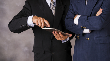 Young happy businessmen dressed in suit working on his tablet or touchpad in office.の写真素材