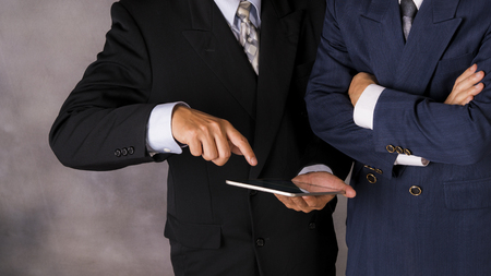 Young happy businessmen dressed in suit working on his tablet or touchpad in office.の写真素材