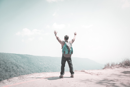 Relaxed backpacker traveler spreading his arms at the edge of mountain,feel free and happy.Concept of vacation,freedom,happiness,enjoyment ,summer and well being.の写真素材