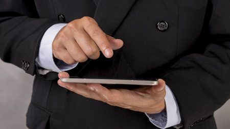 Business man with black suit using telephone or tablet for chech his work.の写真素材