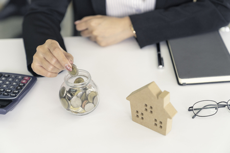 business woman saving for buy house.put coin to glass cup and calculate money.の写真素材