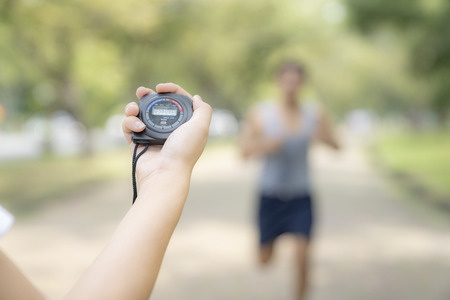 hand holding timer watch for jogging in park.