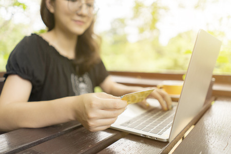 Young woman holding plastic credit card and using laptop computer for shopping online at coffee shop.green screen is clipping path.の写真素材