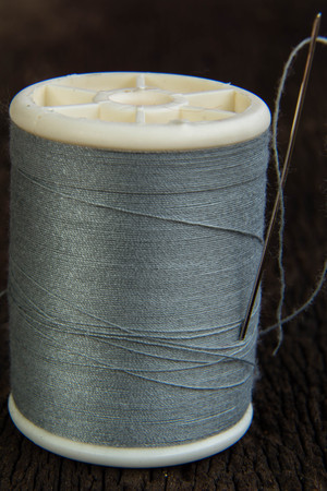 Spools of thread with needles on wooden backgroundの写真素材