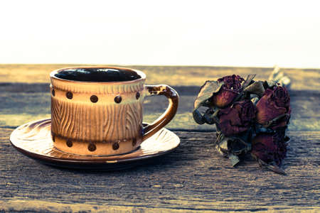 Cup of coffee brown dried rose on old wooden tableの写真素材