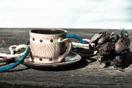Cup of coffee brown dried rose on old wooden tableの写真素材
