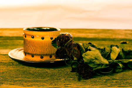 Cup of coffee brown dried rose on old wooden tableの写真素材