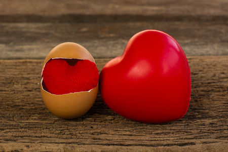 Broken egg and heart on old wood is pulled outの写真素材