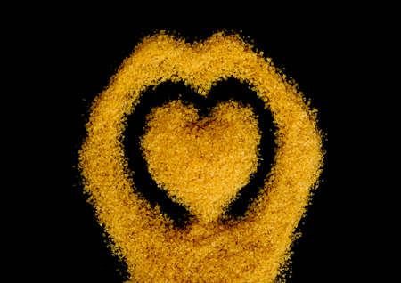 Heart shape of brown sugar on black backgroundの写真素材