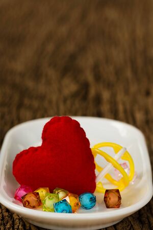 Red Heart and Colorful beads on a white plateの写真素材