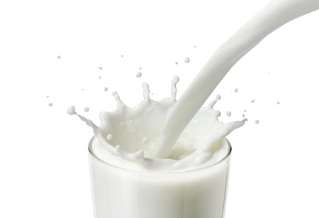 pouring milk or white liquid in a glass created splash in white background or isolated の写真素材