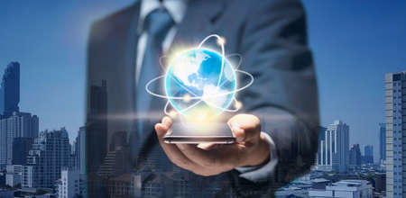 Businessman search Global world by internet network on mobile phone. Man hold smart Phone connect to planet earth show USA world map for Smart business, Earth connect technology, Internet 5G concept.の写真素材