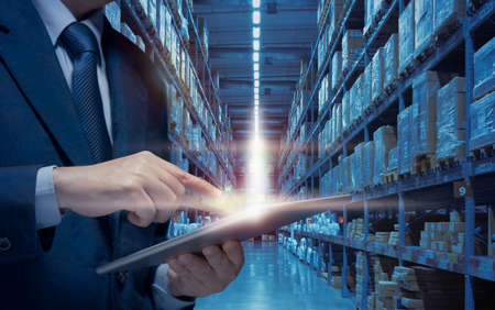 Businessman use tablet to plan, check, control of logistics transportation in warehouse. Business man manage warehouse by internet Technology show Modern warehouse, Distribute network business conceptの写真素材