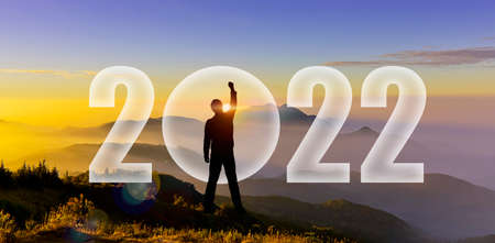Happy new year 2022. Silhouette of man hands up to challenge 2022 on mountain hill. Man Silhouette...