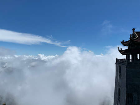 A view of a tower in the clouds from the top of the mountainの写真素材