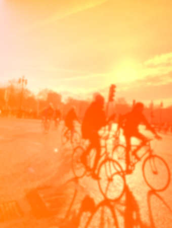 blurred image of people riding bicycles in the city at sunset.の写真素材