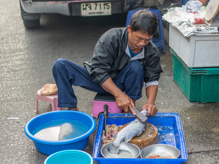 Bangkok, Thailand - January 25, 2015 Unidentified seller is cleaning fish for customer on street market in the morning at Houay Kwang area.のeditorial素材