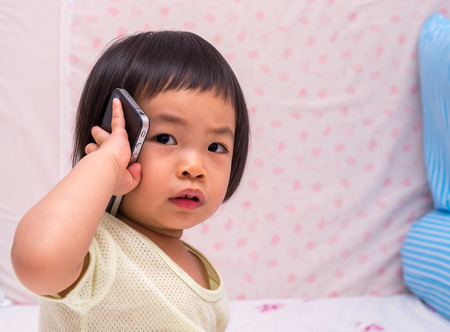 Asian toddler girl with cell phoneの写真素材