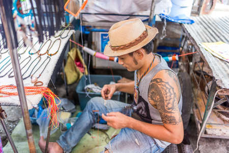 Bangkok, Thailand - Nov 14, 2015 Unidentified man is making textile necklace for sell on street of Chatuchak, the biggest weekend market in South East Asia.のeditorial素材