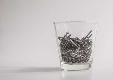 Nails in glass as concept feeling pain of drinking.の写真素材