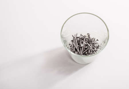 Nails in glass as concept feeling pain of drinking.の写真素材