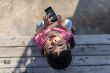 3 years olds little Asian girl with smartphone in her holidayの写真素材