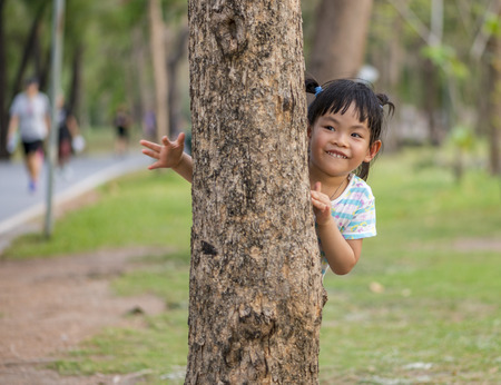 Thai little girl with 3.6 years play hide and seek in a parkの写真素材