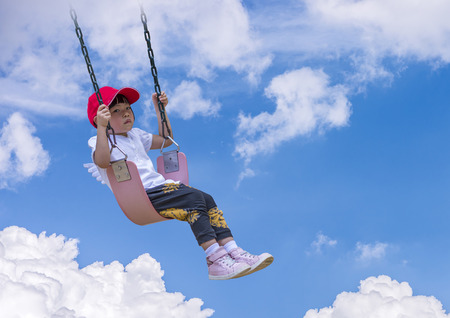 Moody little angel  girl plays swingの写真素材