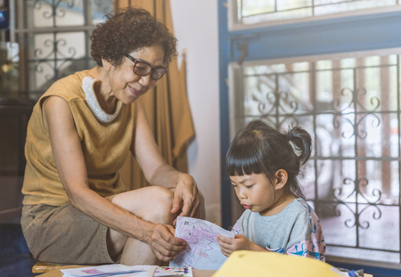 Thai Granddaughter try to read, grandmother smileの写真素材