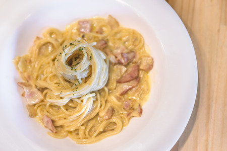 Top view spaghetti carbonara on wood table. Image is warm and looks healthy. Bacon and ham mixed in the  spaghetti. Close up to spaghetti.の写真素材