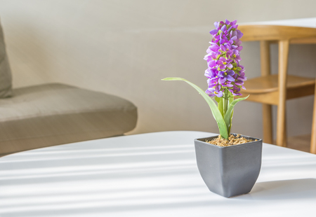 Purple Artificial Flowers in small pot on white table or Artificial Arpophyllum in small pot on white table. Light come from left side of the image.の写真素材