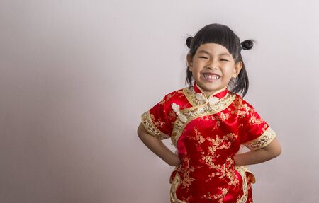 Big smile little girl in Chinese dress for Chinese New Year theme. Little girl in funny action, hands on waist.の写真素材