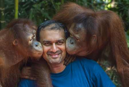 Bangkok, Thailand - Feb 26, 2018 Two monkeys kiss a tourist man at Safari world zoo. Two monkeys or orangutan kiss the tourist man on both cheek.のeditorial素材