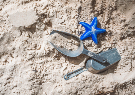 Beach toys on beach sand, a blue starfish and metal shovelの写真素材