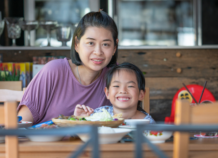Mother and daughter in a restaurant. Happy time toghter at table food.の写真素材