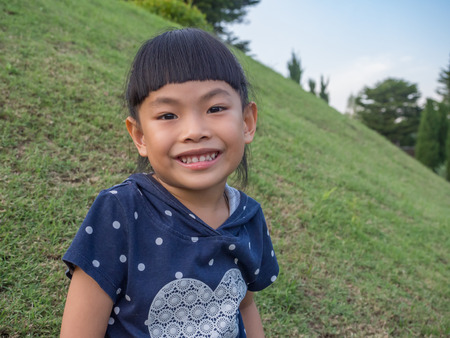 Smiley face Asian little girl in a park.の写真素材